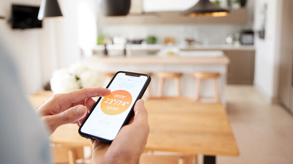 Mann mit App auf Smart Phone steuert seine Zentralheizung