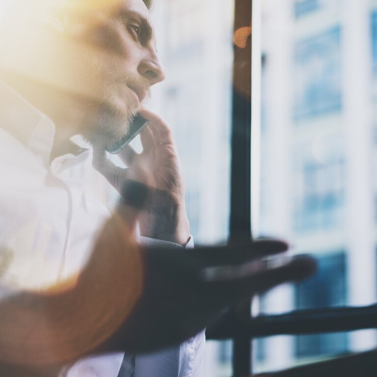 Telefonat in einem modernen Büro während Sonnenlicht durch das Fenster fällt.
