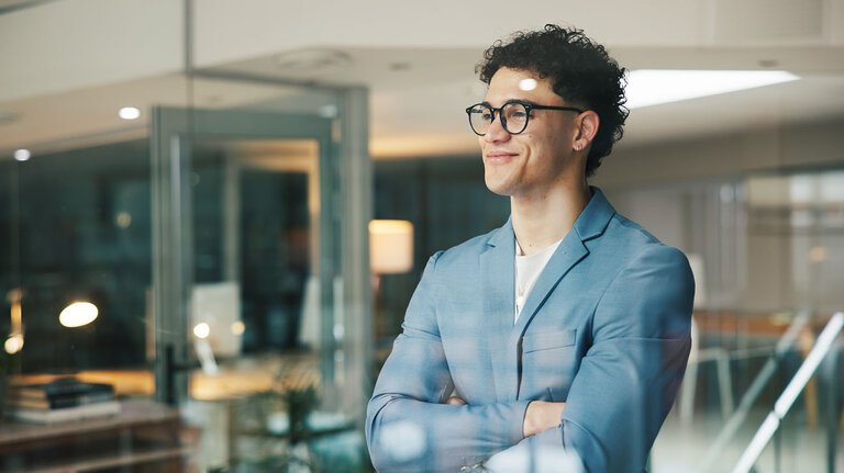 Nachdenkender Geschäftsmann am Schreibtisch vor dem Fenster – stolzer Blick und Vision für das Wachstum des Unternehmens. Ideen, Ehrgeiz und ein lächelnder Manager für die Unternehmensentwicklung, Planung und den Traum vom zukünftigen Erfolg