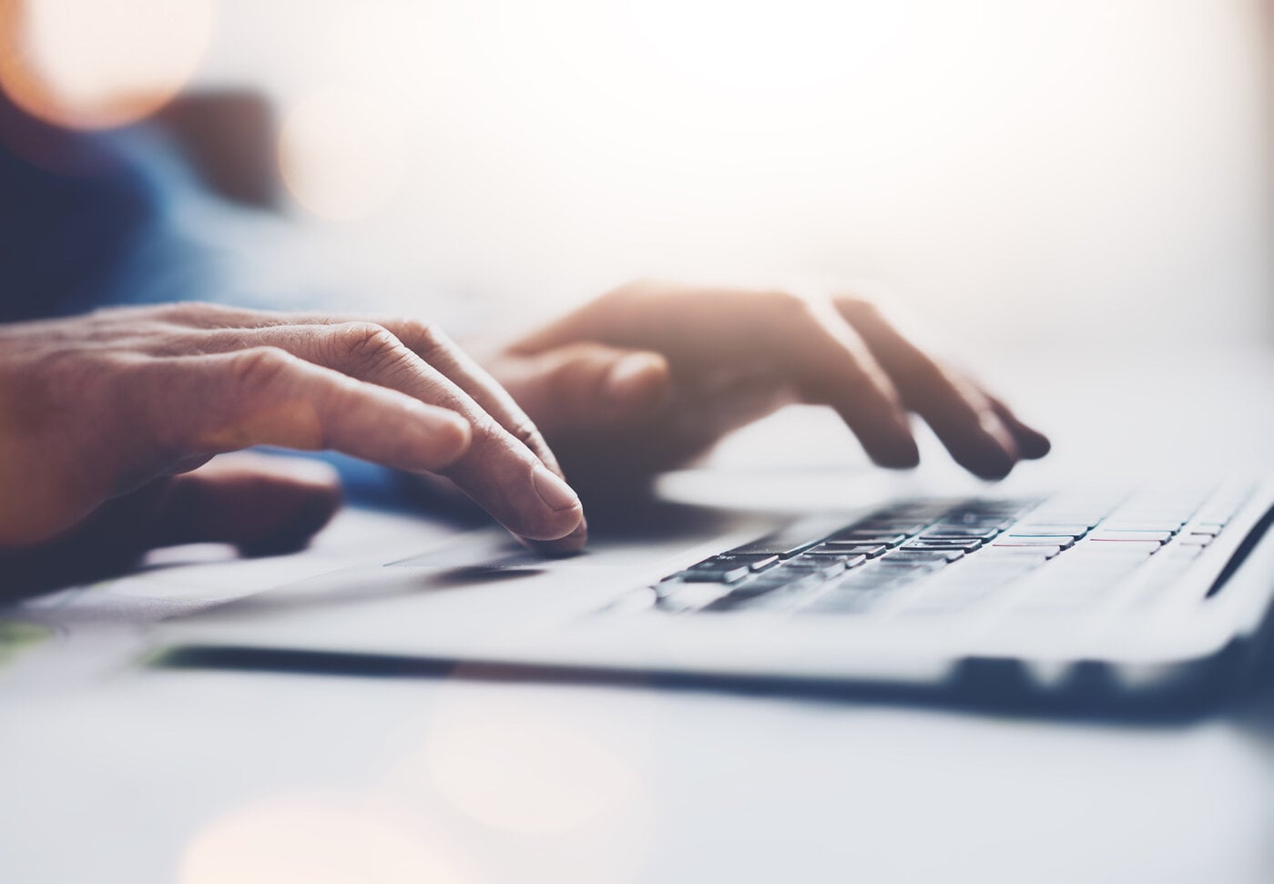 Eine Nahaufnahme von Händen, die auf einer Laptop-Tastatur tippen, symbolisiert digitale Kommunikation und moderne Arbeitsmethoden.