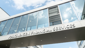 Moderne Glasfassade mit dem Schriftzug Volkswagen Financial Services, aufgenommen unter blauem Himmel.