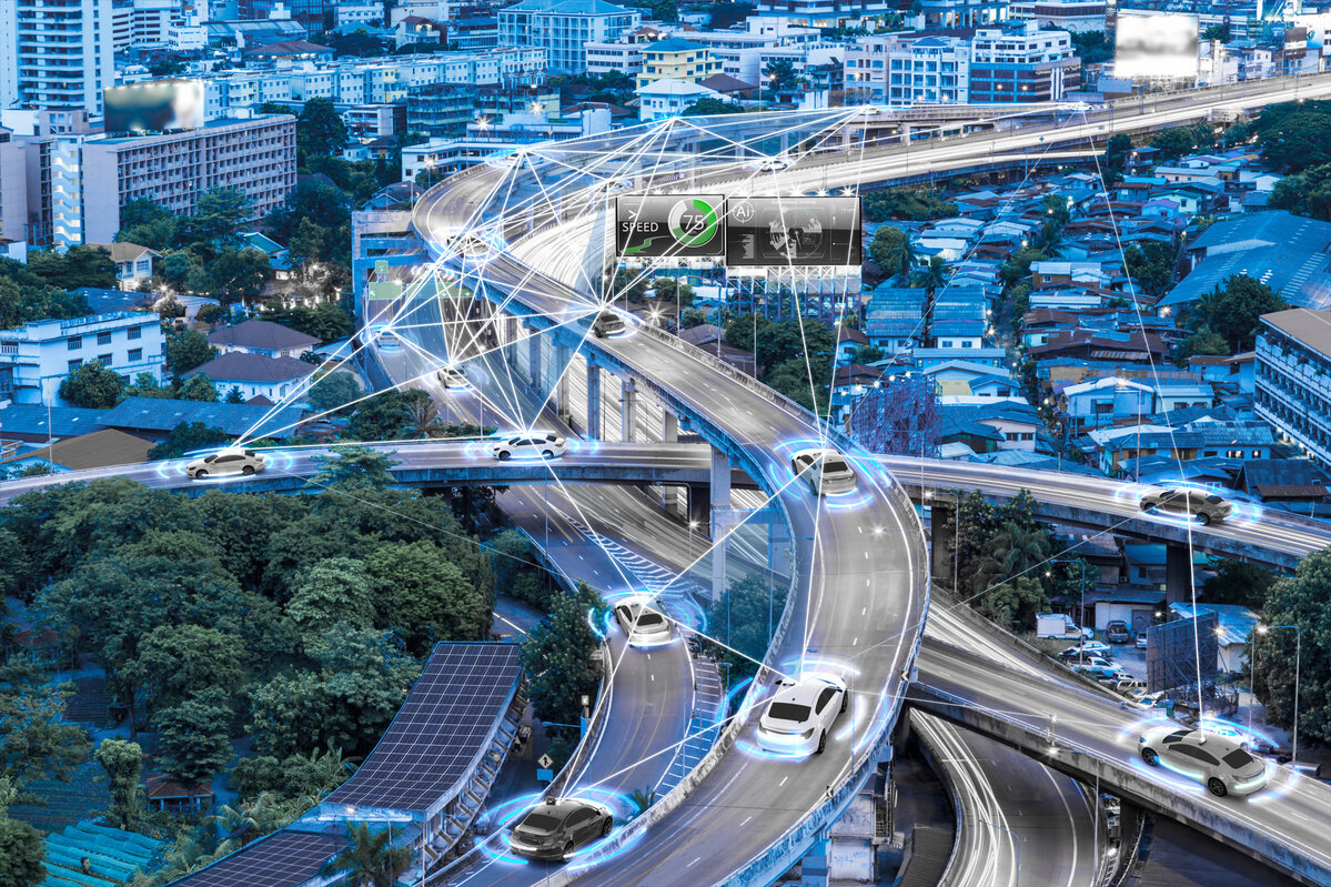Vernetzte Autobahn mit autonomen Fahrzeugen, die durch digitale Linien und Symbole miteinander kommunizieren, im urbanen Hintergrund.