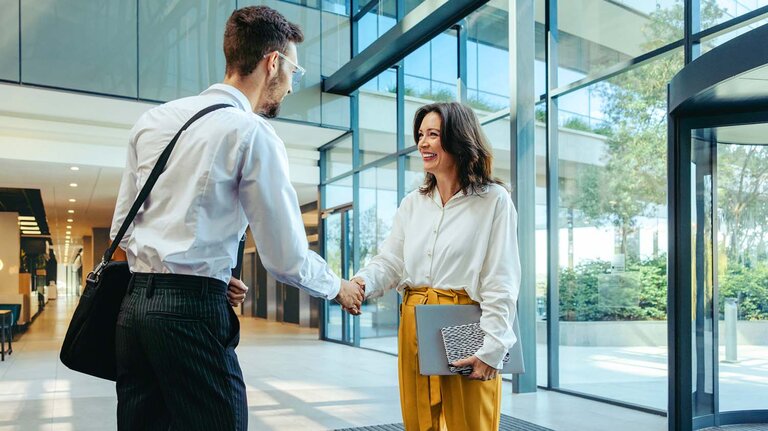Berufskollegen treffen sich in der Lobby eines modernen Bürogebäudes