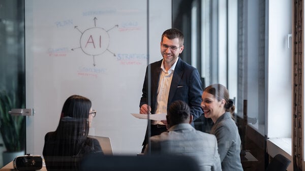 Ein vielfältiges Geschäftsteam in einem modernen Büro während einer Besprechung, bei der die Strategie im Bereich künstliche Intelligenz erörtert wird. Konzept der KI-Innovation, Teamarbeit, Führung, Unternehmensplanung, professionelle Zusammenarbeit