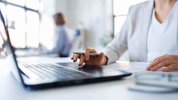Konzept „Business und Menschen“ – Geschäftsfrau mit Laptop und Unterlagen bei der Arbeit im Büro