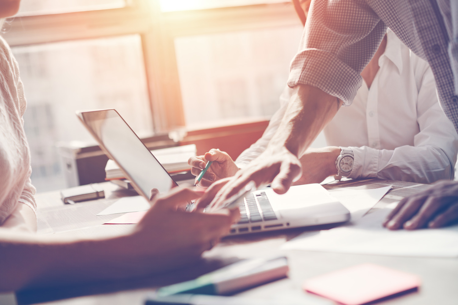 Teamarbeit im Prozess – Brainstorming zur Marketingstrategie. Kombination aus Papierunterlagen und digitalen Geräten im Büro. Mit bewusst eingesetztem Sonnenlicht-Effekt.
