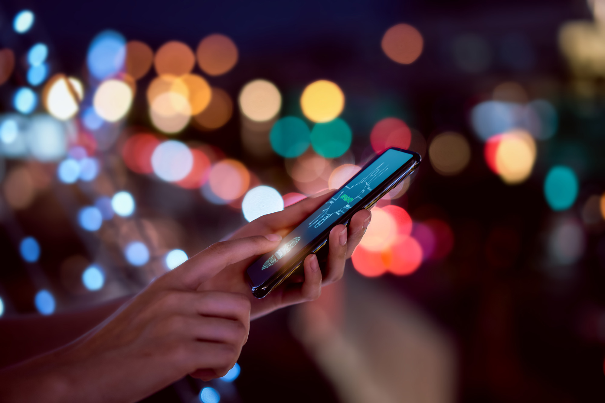 Nahaufnahme von Händen, die einen Fingerabdruck auf einem Smartphone scannen, um das Mobiltelefon zu entsperren – im Hintergrund verschwommene, farbige Lichter einer nächtlichen Stadt. Symbolbild für Sicherheit durch Identitäts-Technologie.