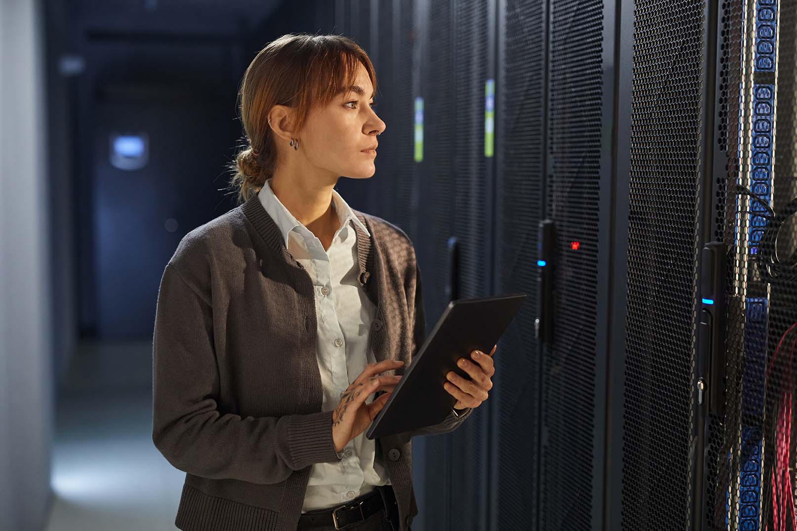 Frau mit Tablet überprüft Server-Racks in einem KRITIS-Unternehmen.