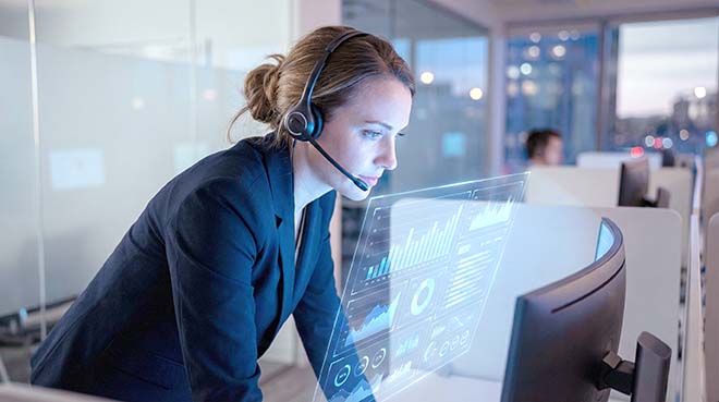 Eine professionelle Mitarbeiterin mit Headset überwacht in einem modernen Kontrollraum Echtzeit-Analysen auf einem futuristischen holografischen Dashboard und verbessert so den Kundenservice